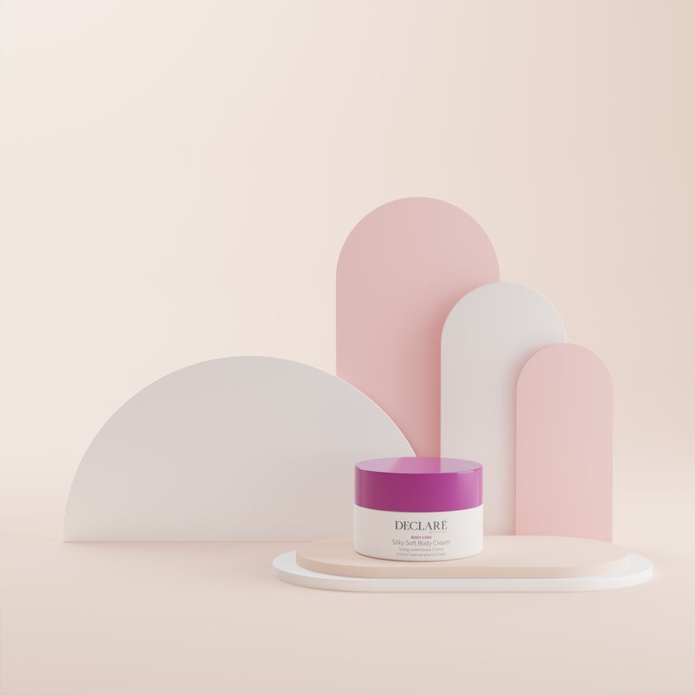 Pot blanc avec couvercle violet sur socle. Formes décoratives roses et blanches en arrière-plan. Logo DECLARÉ visible.