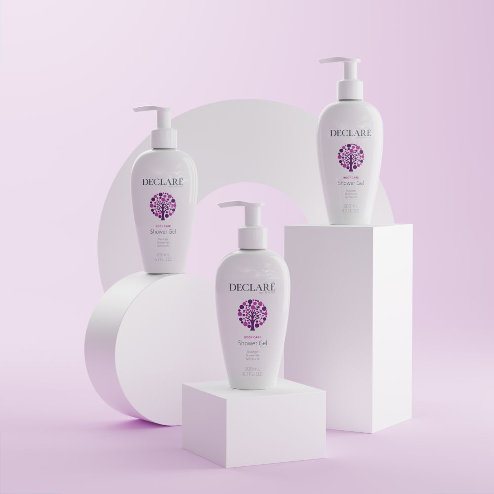 Trois flacons DECLARÉ blancs avec pompe sur socles. Fond: formes blanches et surface rose. Produit: Shower Gel.