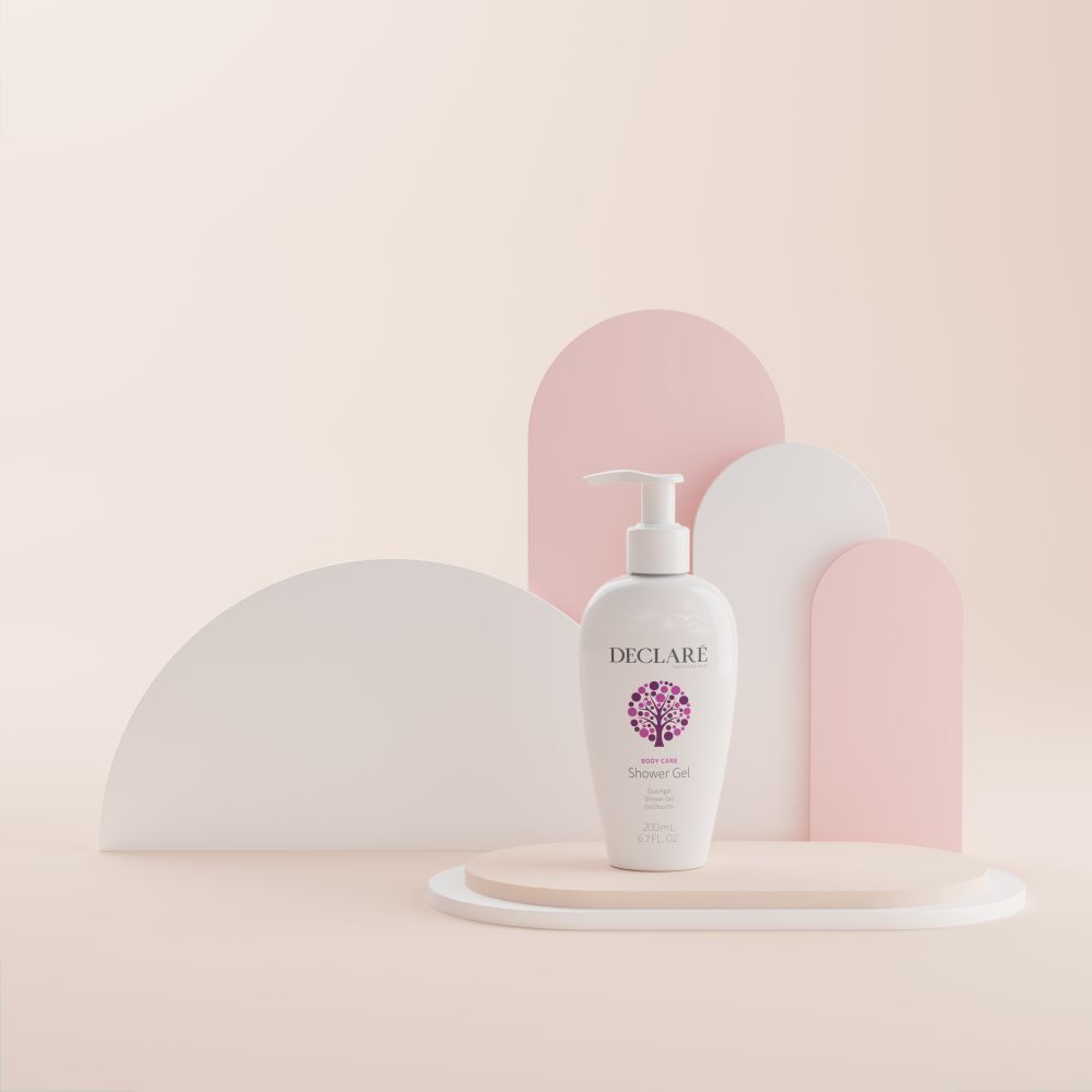 Flacon DECLARÉ blanc avec pompe sur socle. Fond: formes roses, blanches et roses. Produit: Shower Gel.