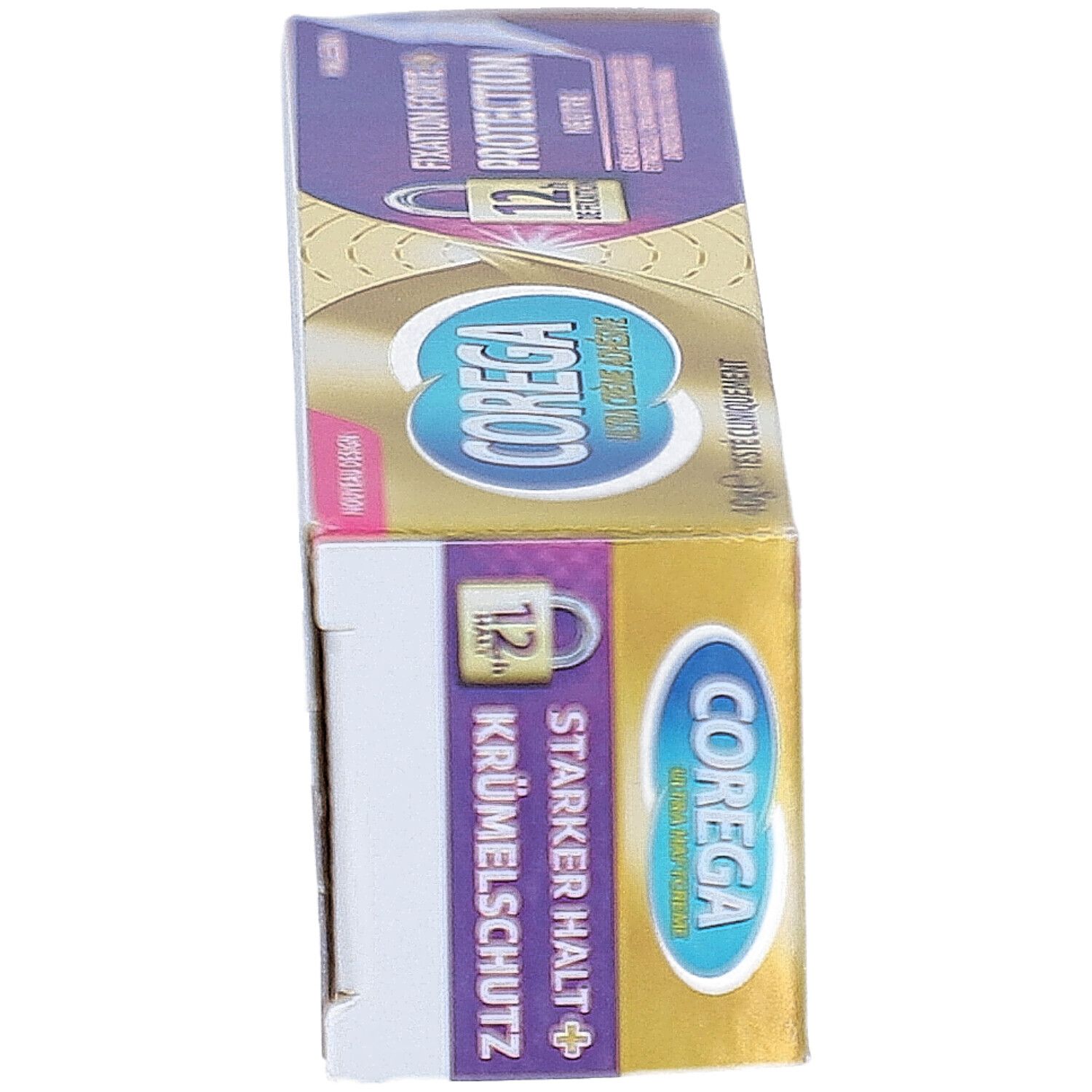 Boîte de crème adhésive COREGA ULTRA, en biais. Or, violet, texte. Texte : Fixation forte + protection, 12h tenue. Nouveau design.