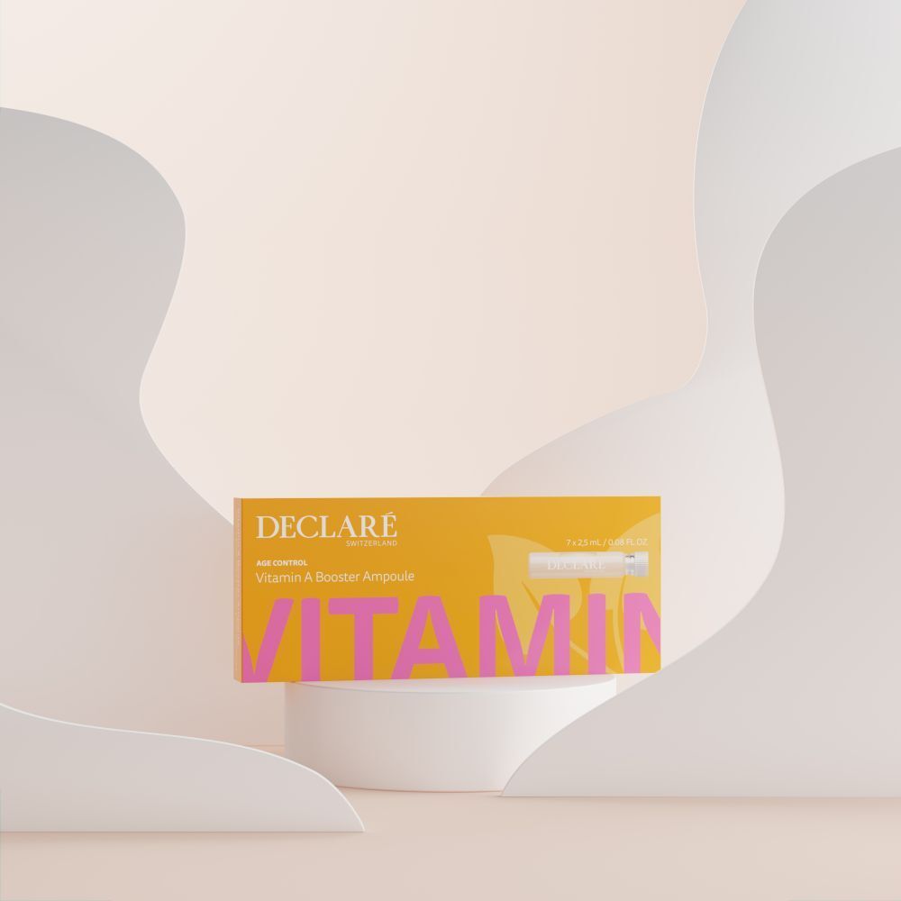 Boîte jaune DECLARÉ Vitamin A Booster Ampoule sur socle. Inscription rose "VITAMIN". Fond avec formes.
