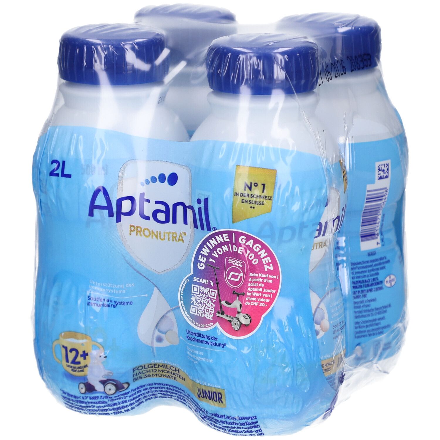 Quatre bouteilles Aptamil Junior emballées. Bouteilles bleues avec bouchons bleus. Inscriptions: Aptamil, Pronutra, 12+.