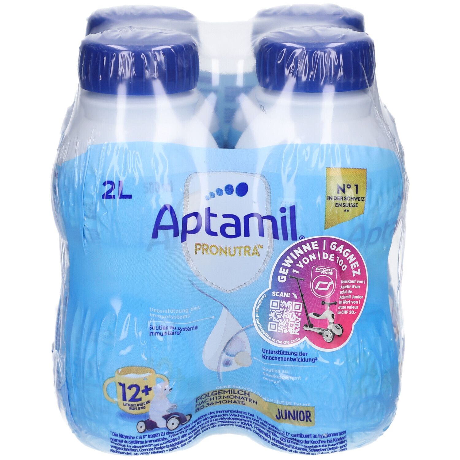 Quatre bouteilles Aptamil Junior emballées. Bouteilles bleues avec bouchons bleus. Inscriptions: Aptamil, Pronutra, 12+.