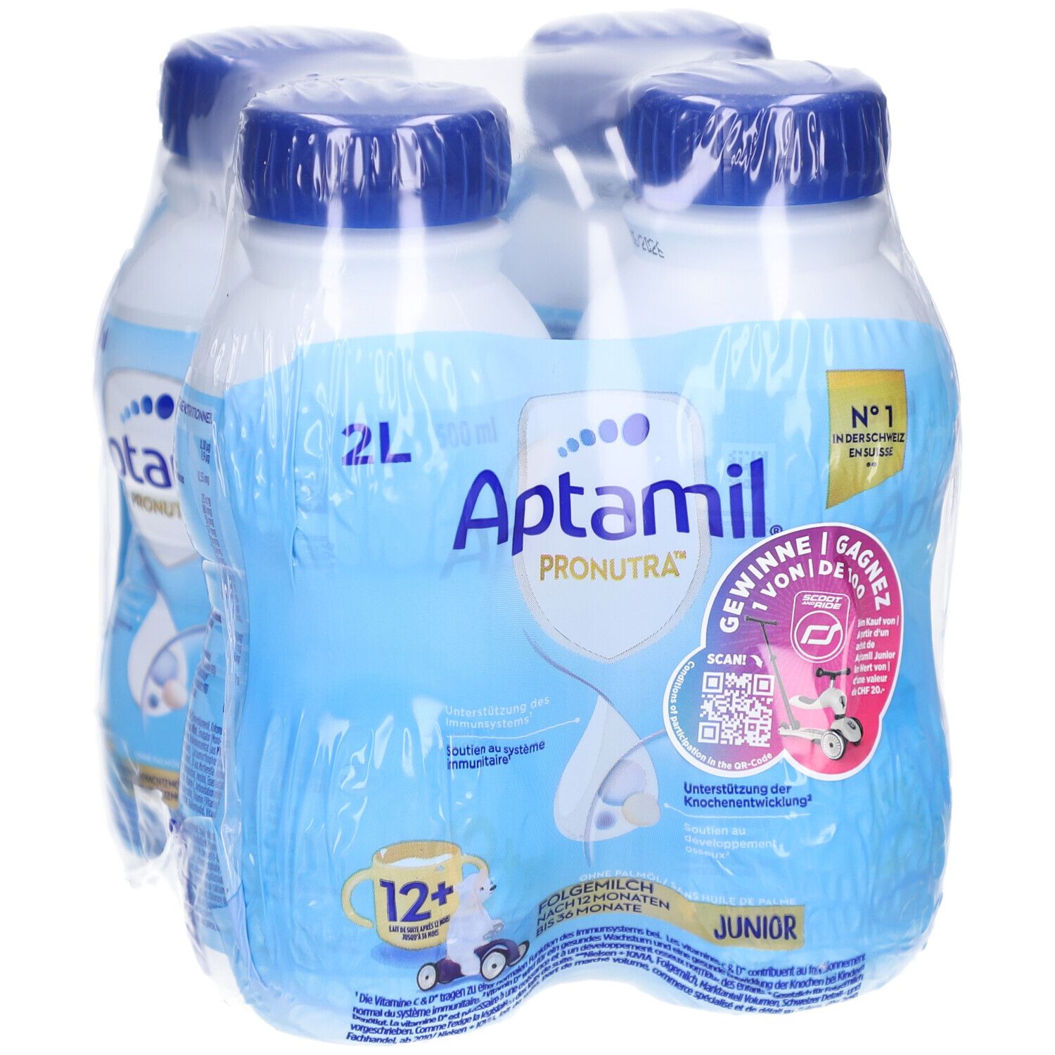 Quatre bouteilles Aptamil Junior emballées. Bouteilles bleues avec bouchons bleus. Inscriptions: Aptamil, Pronutra, 12+.