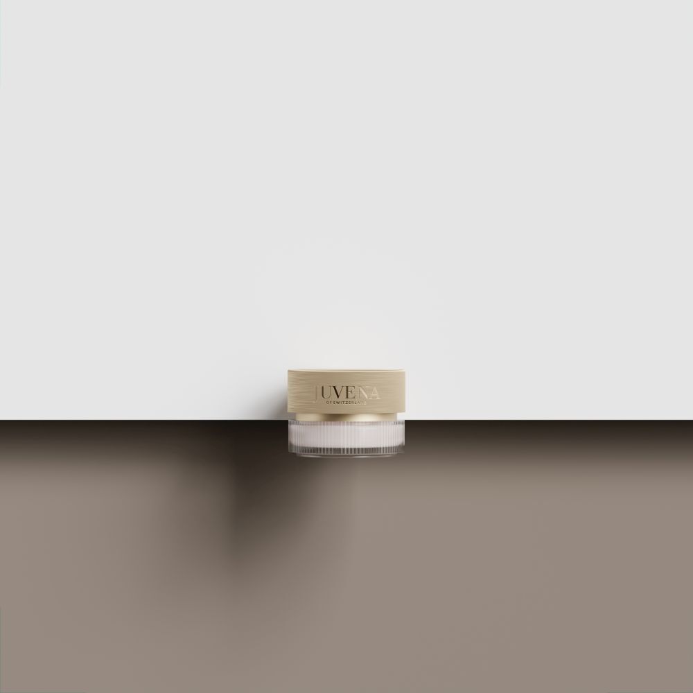 Creme-Tiegel mit goldfarbenem Deckel. Aufschrift: JUVENA. Der Tiegel steht auf einer braunen Oberfläche.