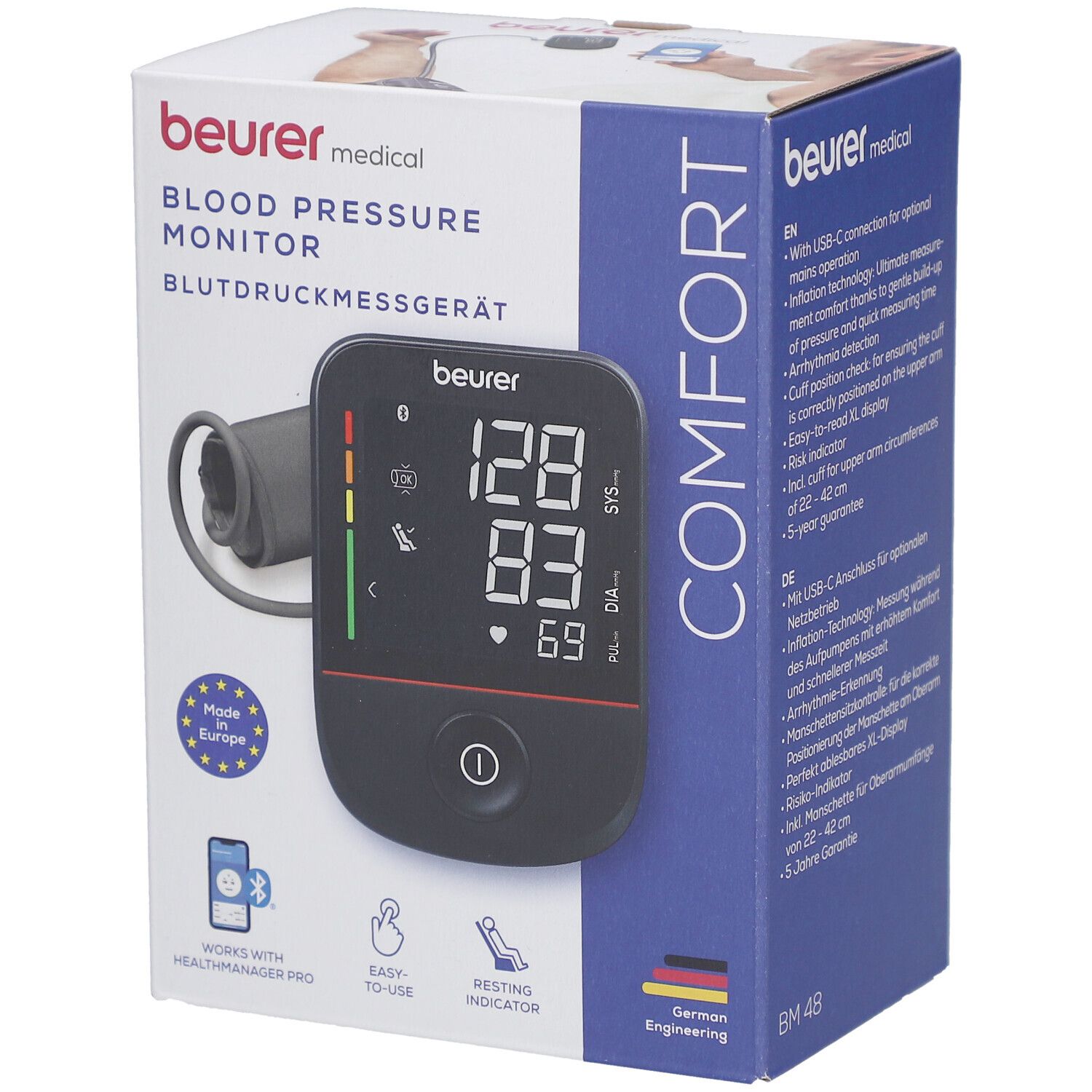 Blutdruckmessgerät in Verpackung. Schwarzes Display mit Messwerten. Marke: beurer. Aufdruck: Blutdruckmessgerät, Comfort, Made in Europe.