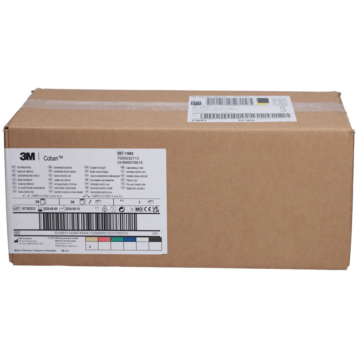 Braune Kartonverpackung mit Etiketten. Auf dem Etikett steht "3M Coban". Weitere Informationen und Barcodes sind ebenfalls sichtbar.