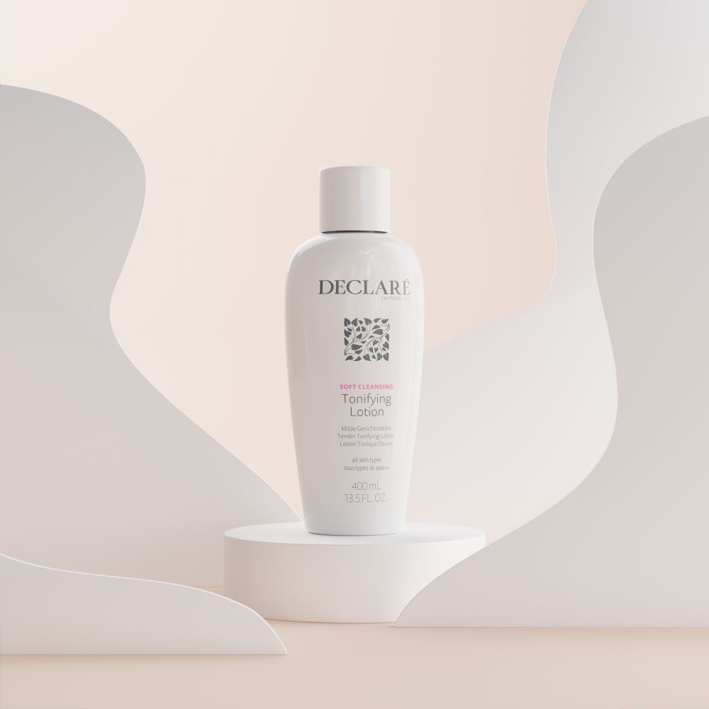 Flacon blanc avec bouchon sur un socle. Inscription : DECLARÉ, logo, Toning Lotion. Fond avec des formes blanches et beiges.