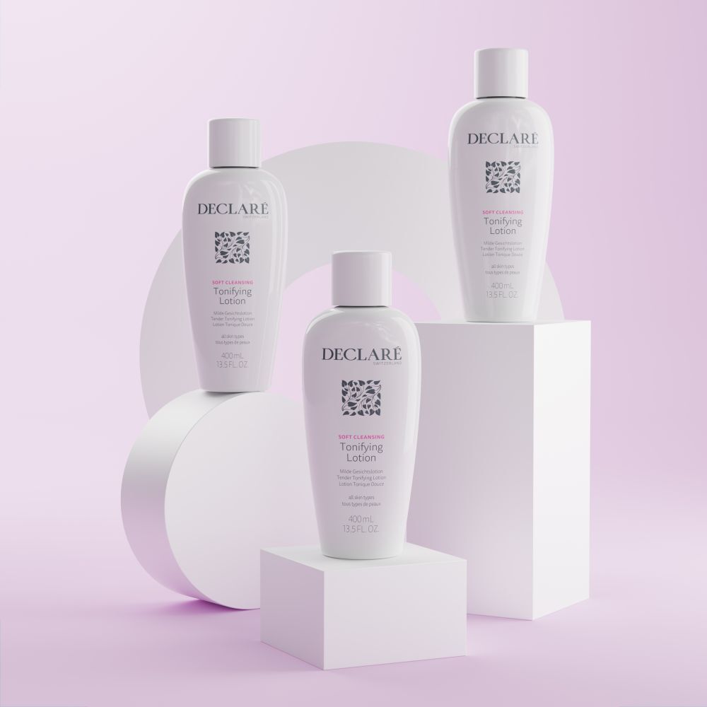 Trois flacons blancs avec bouchons sur des socles. Inscription : DECLARÉ, logo, Toning Lotion. Fond : blanc et rose.