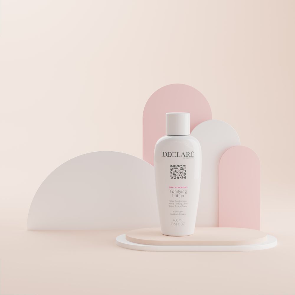 Flacon blanc avec bouchon sur un socle. Inscription : DECLARÉ, logo, Toning Lotion. Fond : beige, rose et blanc.