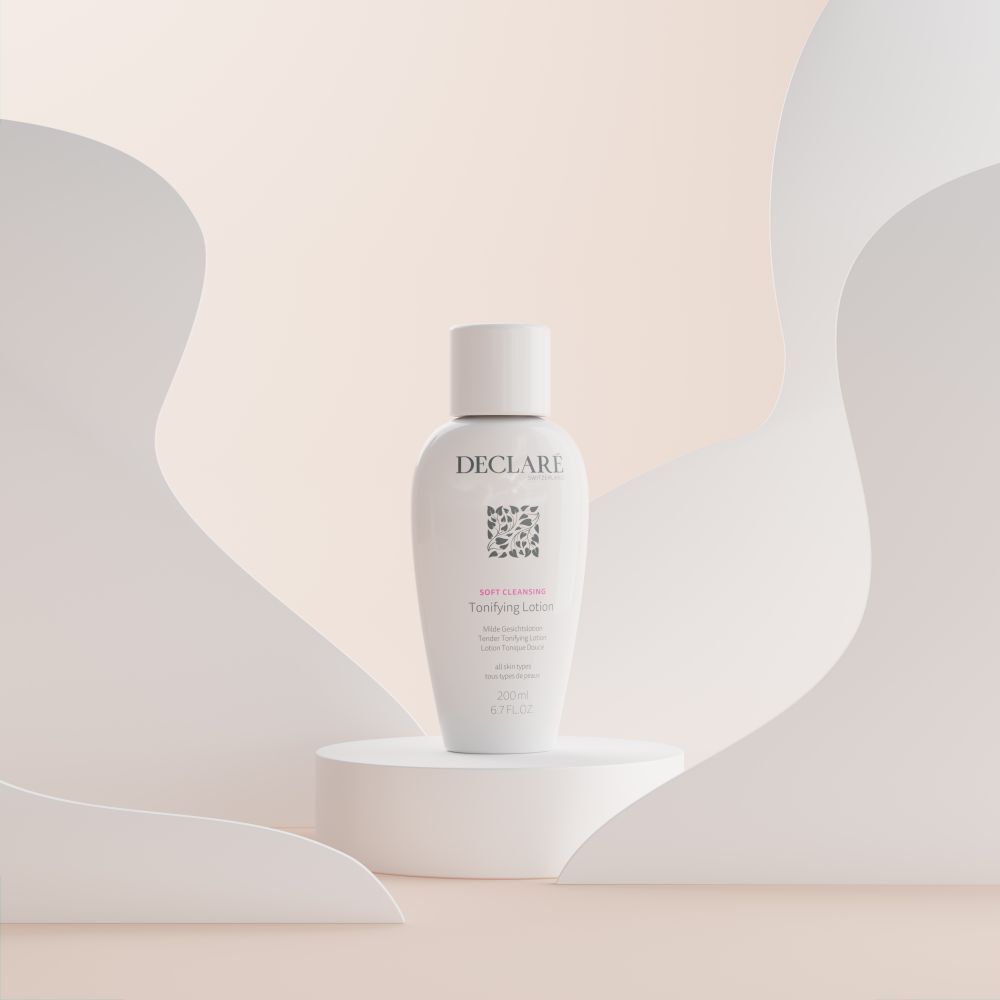 Flacon blanc DECLARÉ Toning Lotion sur socle. Inscription : Soft Cleansing, Toning Lotion. Fond : formes blanches.