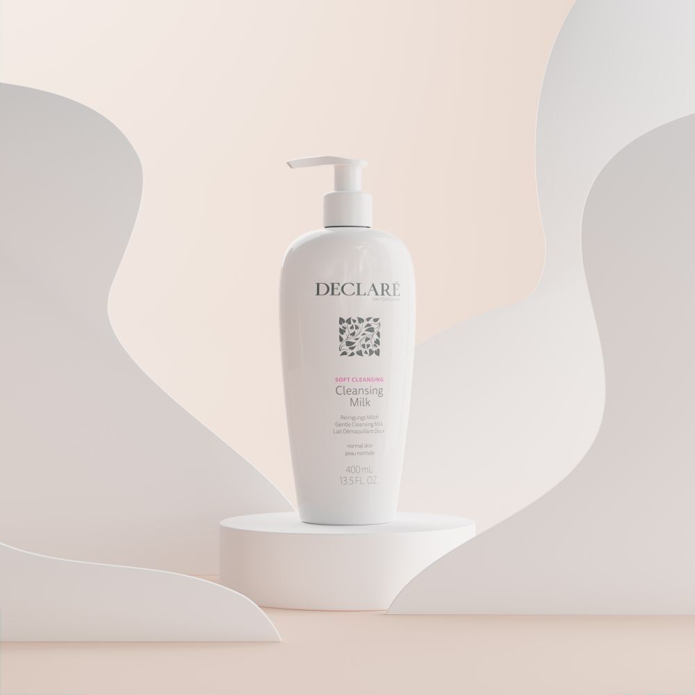 Weiße Flasche mit Pumpe auf Podest. DECLARÉ Cleansing Milk, 400ml. Hintergrund mit weißen Formen.