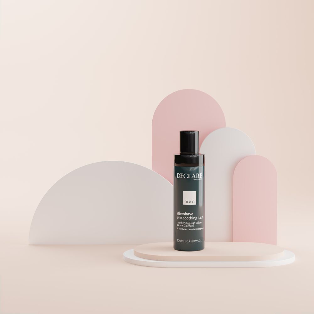 Eine Flasche DECLARÉ Men After-Shave-Balsam. Blau-schwarz. Text: aftershave skin soothing balm. Auf Podest.