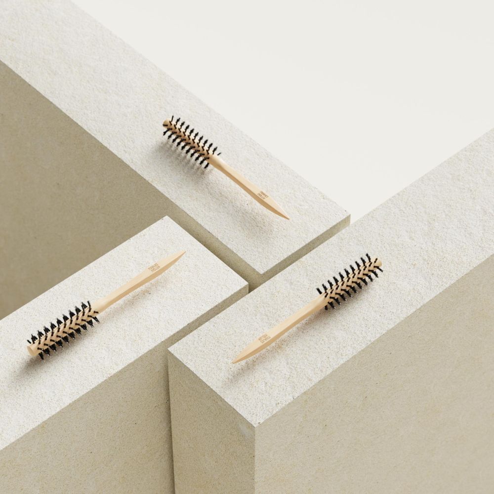 Trois brosses à cheveux rondes sur blocs blancs. Manche en bois, poils noirs. Pas de marque visible.
