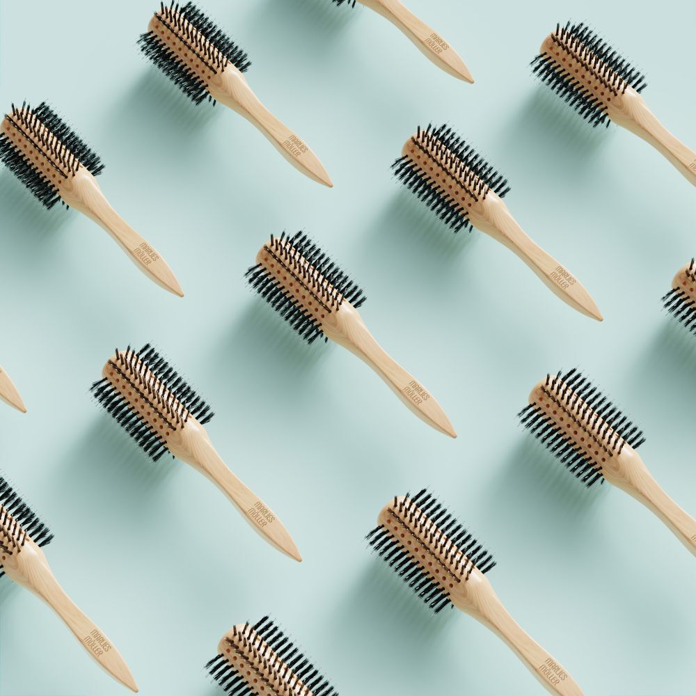 Plusieurs brosses à cheveux rondes sur fond bleu clair. Manche en bois, soies noires.