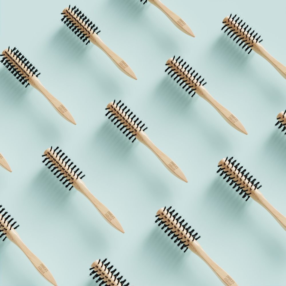 Plusieurs brosses à coiffer sur fond bleu clair. Manche en bois, poils noirs. MARLIES MÖLLER.
