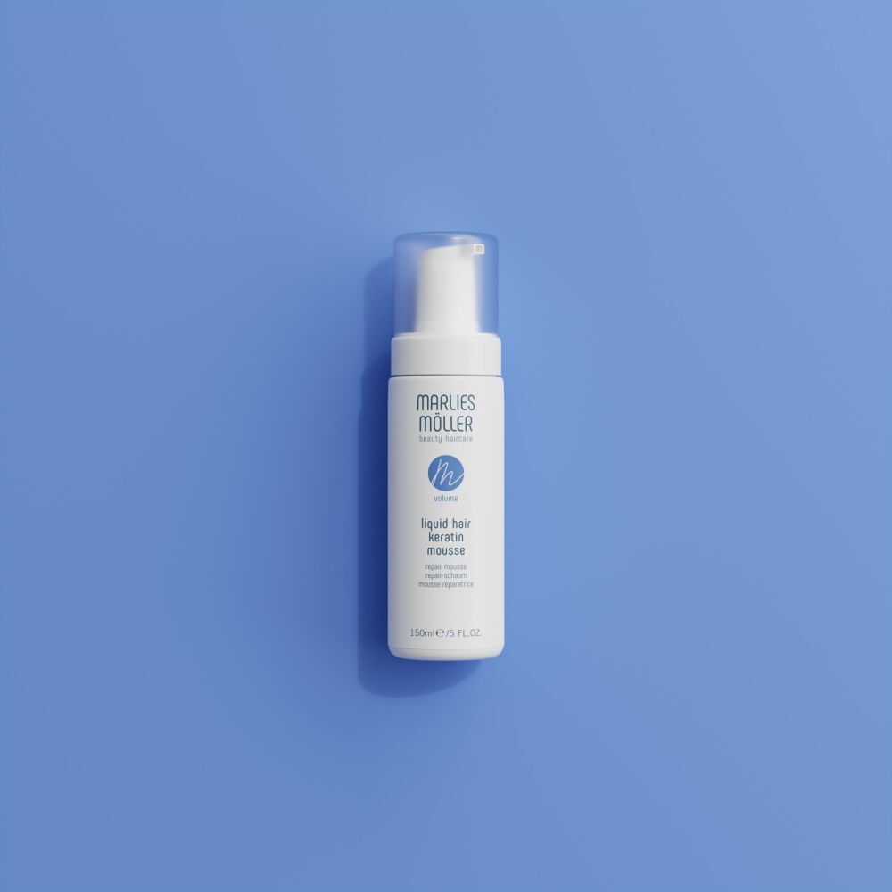 Weiße Flasche mit Sprühkopf. Aufschrift: Marlies Möller, beauty haircare, Volume, Liquid Hair Keratin Mousse. Auf blauem Hintergrund.