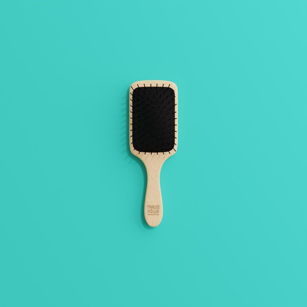 Brosse à cheveux avec manche en bois et coussin noir. Tête carrée. Sur fond turquoise.