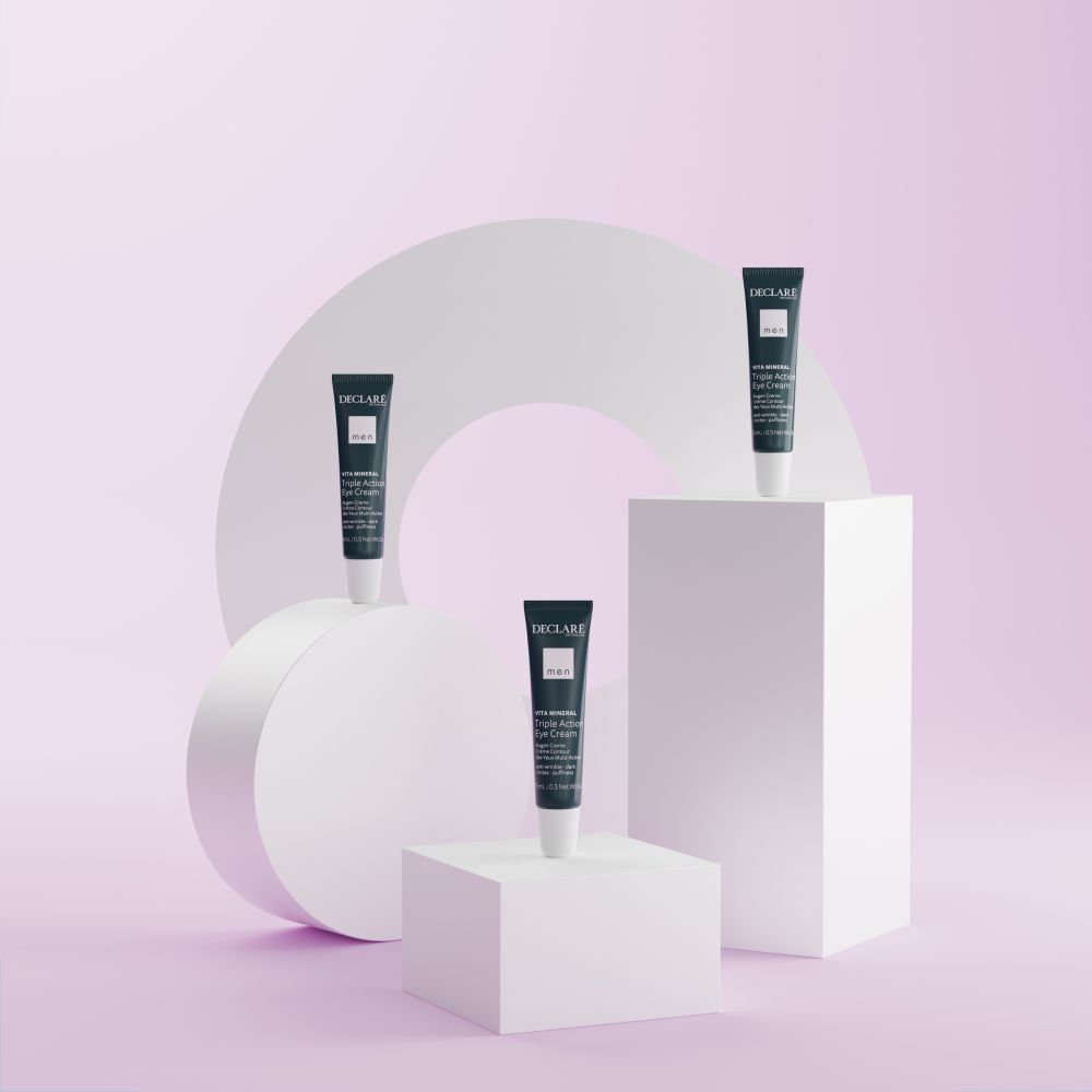 Drei blaue Tuben DECLARÉ Augencreme auf weißen Podesten. Hintergrund mit weißen Formen und Kreisen.