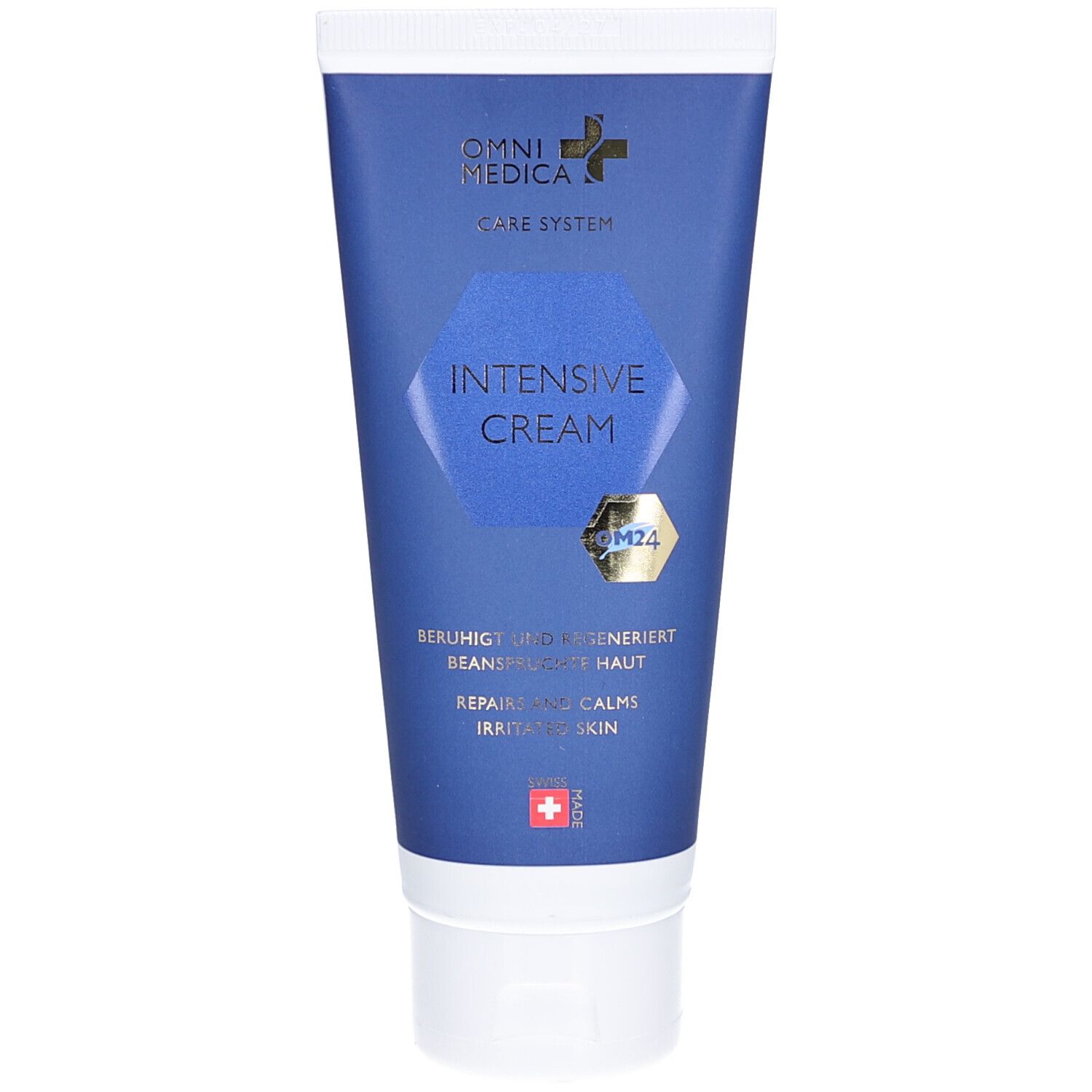 Blaue Tube mit weißem Deckel. Aufschrift: OMNI MEDICA, CARE SYSTEM, INTENSIVE CREAM. Goldfarbenes OM24-Logo. Schweizer Kreuz.