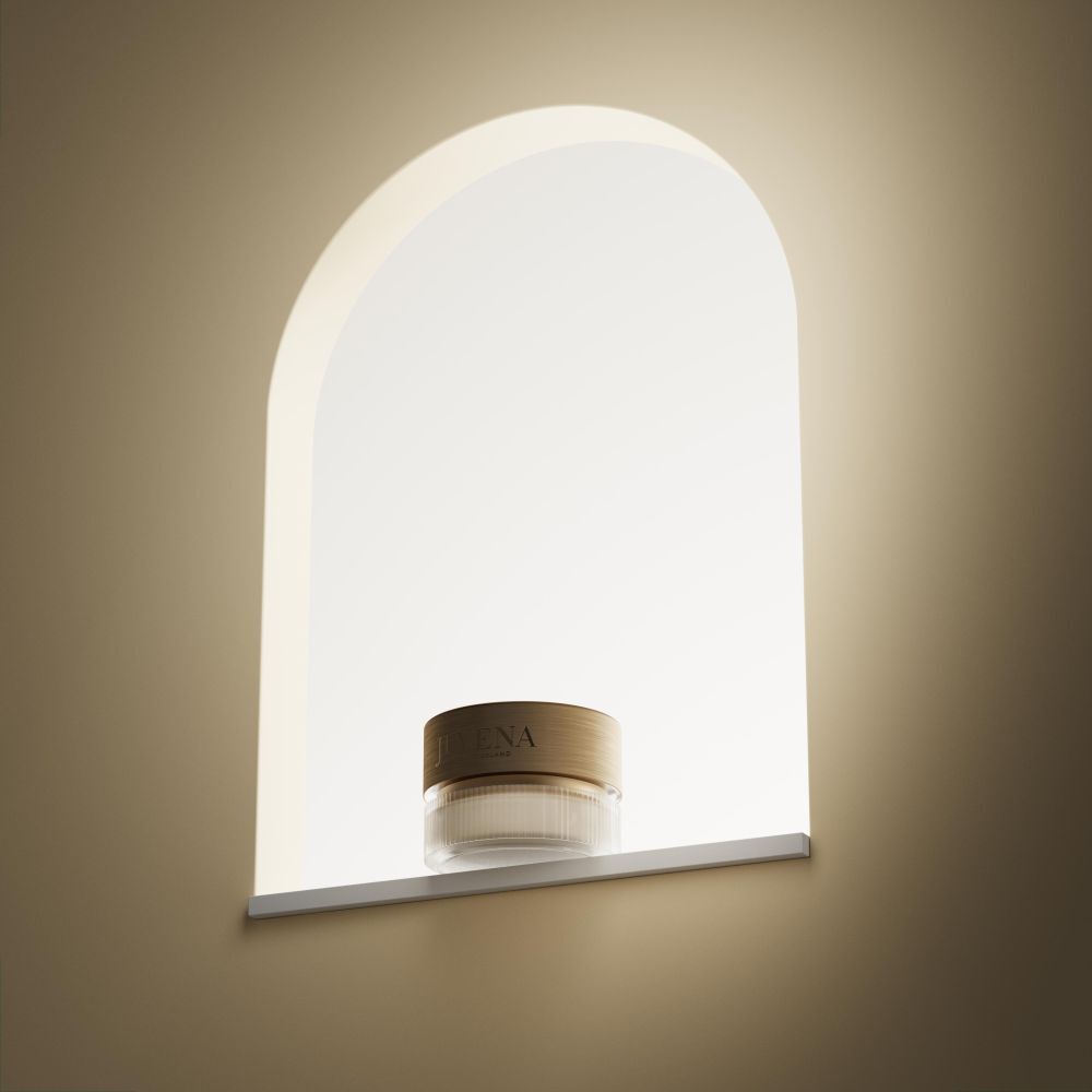 Creme-Glas in Nische. Goldfarbener Deckel. Aufschrift: JUVENA. Auf weißem Regal. Beleuchtete Nische.