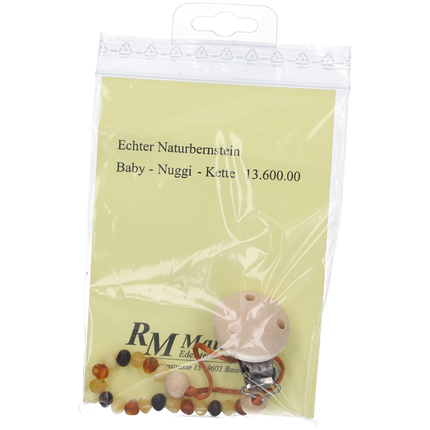 Bernstein-Nuggiketteli in Plastikverpackung. Auf gelbem Papier steht "Echter Naturbernstein Baby - Nuggi - Kette".