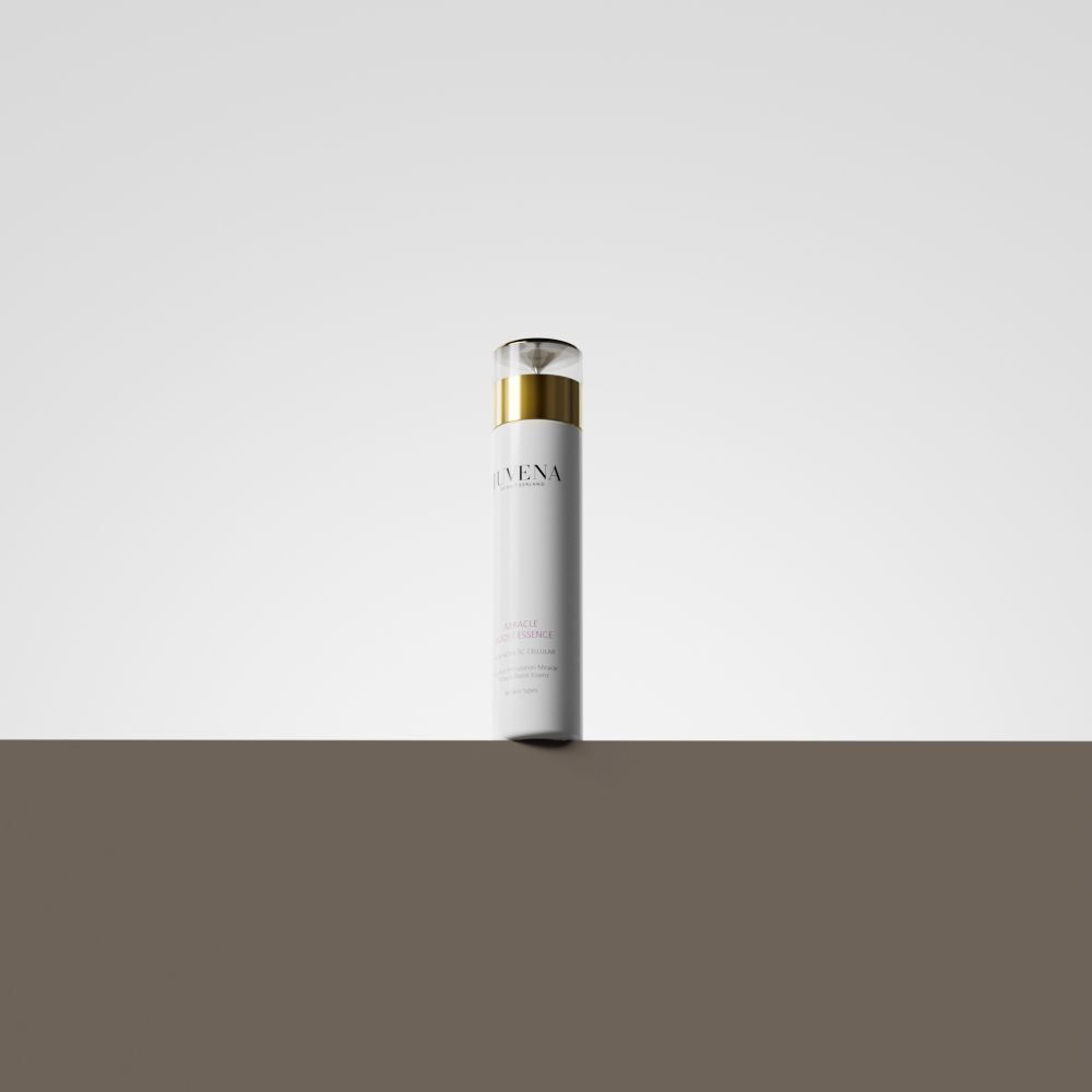 Flacon blanc avec bouchon doré. Inscription : Juvena, Miracle Boost Essence. Sur fond marron.
