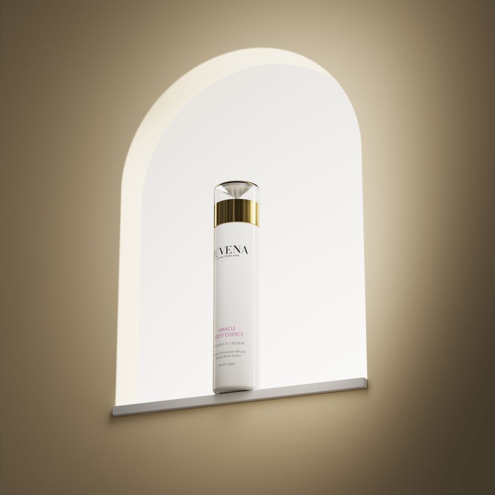 Flacon blanc avec bouchon doré. Inscription : Juvena, Miracle Boost Essence. Dans une niche.