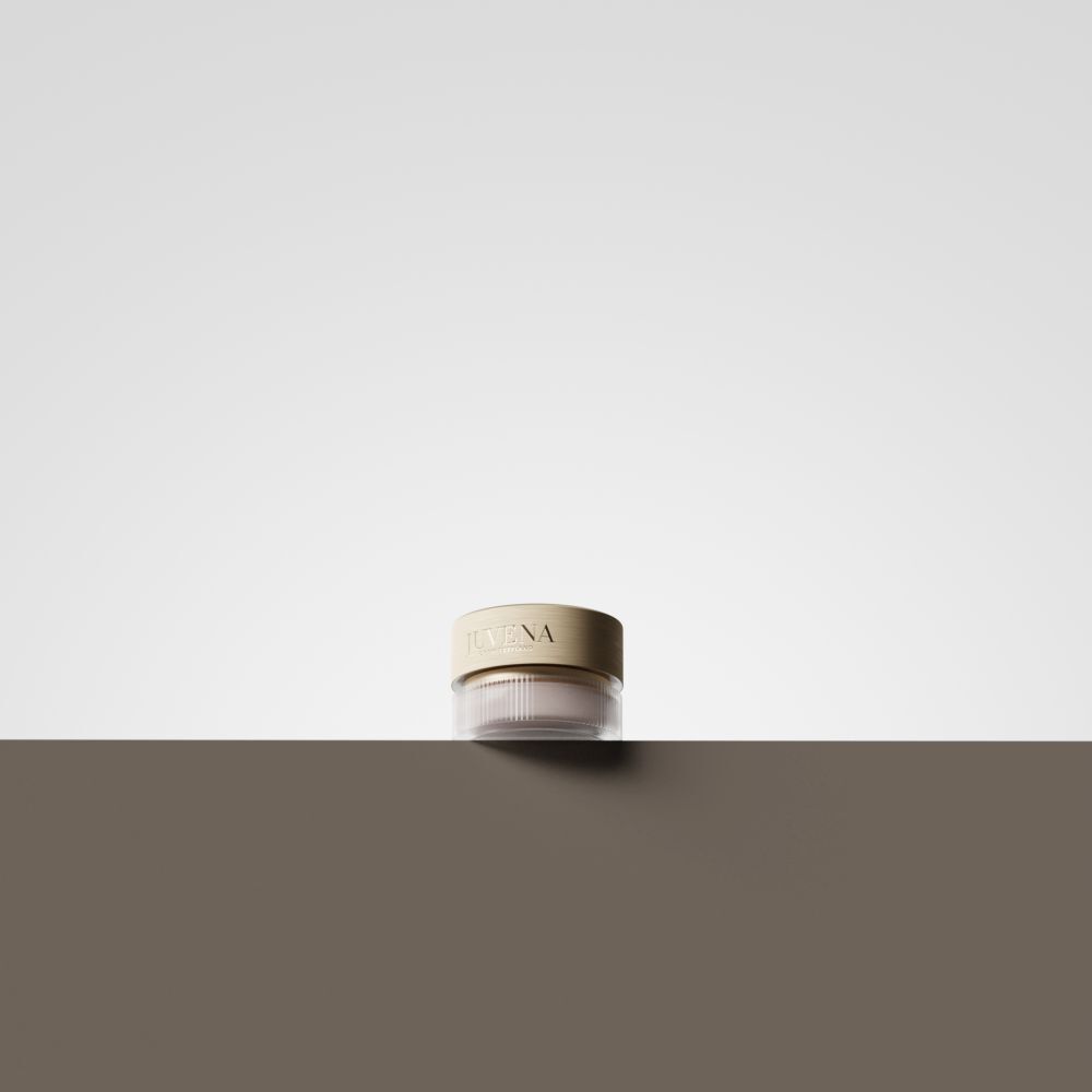 Un pot de crème avec un couvercle doré est posé sur une surface marron. Le fond est blanc.