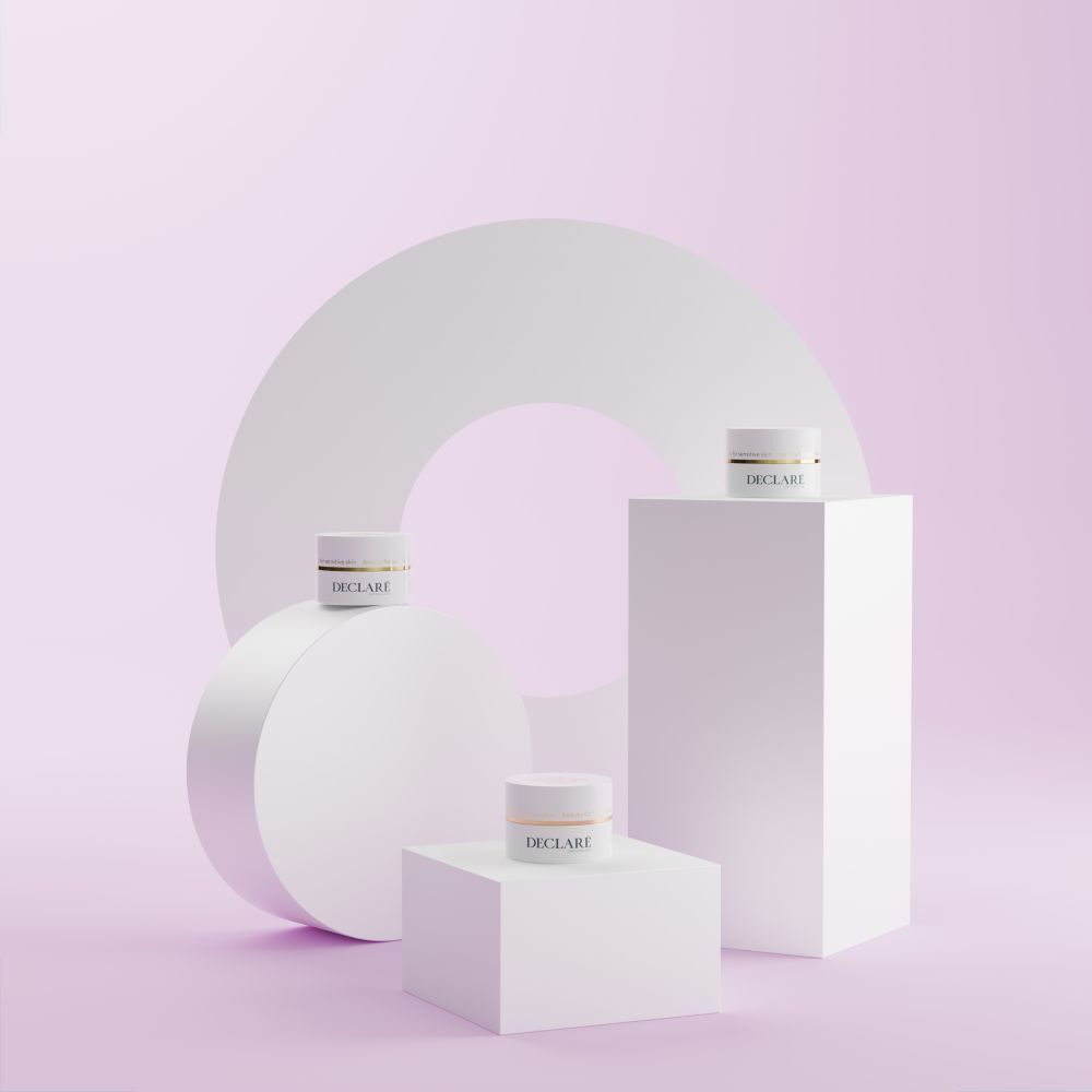 Mehrere weiße Podeste mit weißen Tiegeln. Hintergrund mit geometrischen Formen. DECLARÉ-Logo sichtbar.