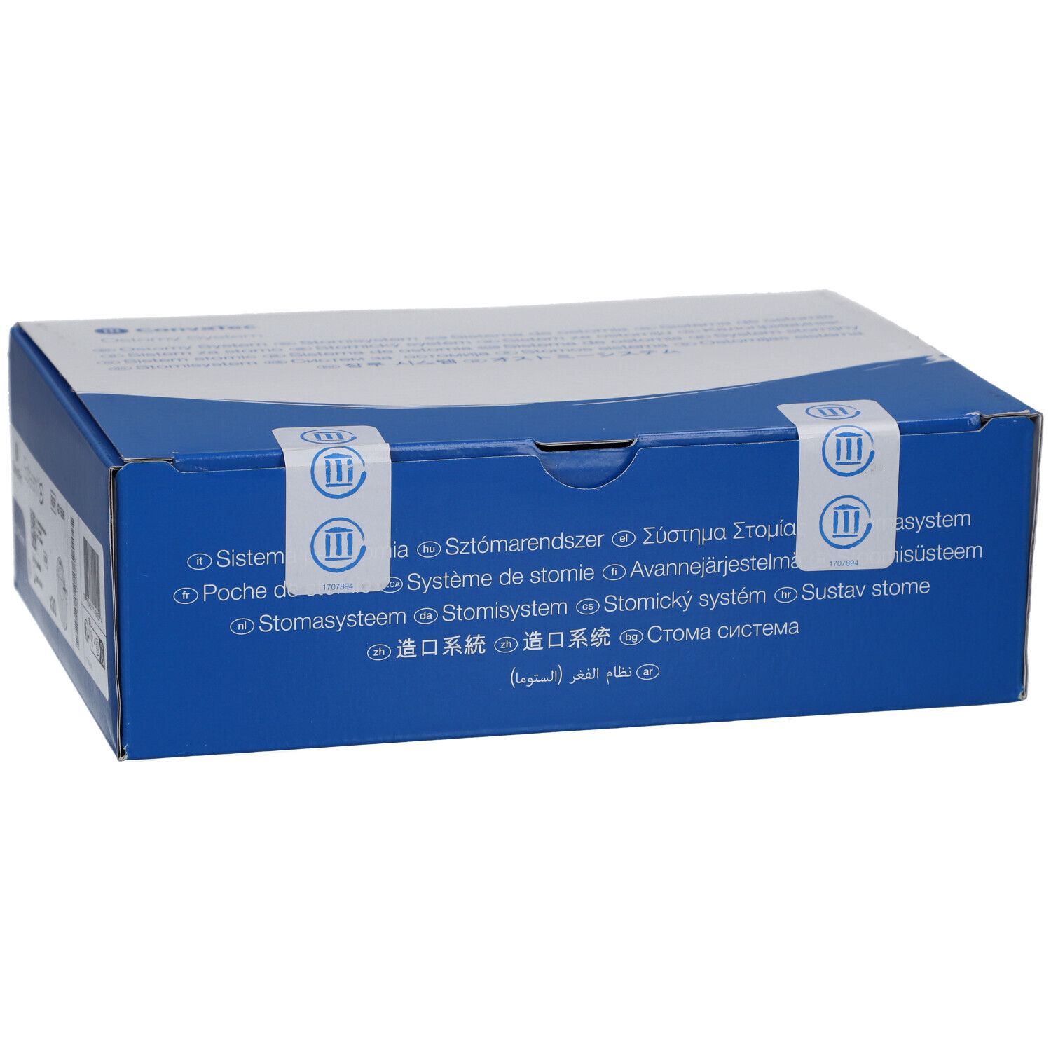 Blaue Schachtel mit weißem Deckel. Aufkleber mit Text in mehreren Sprachen. Siegel mit Logo.