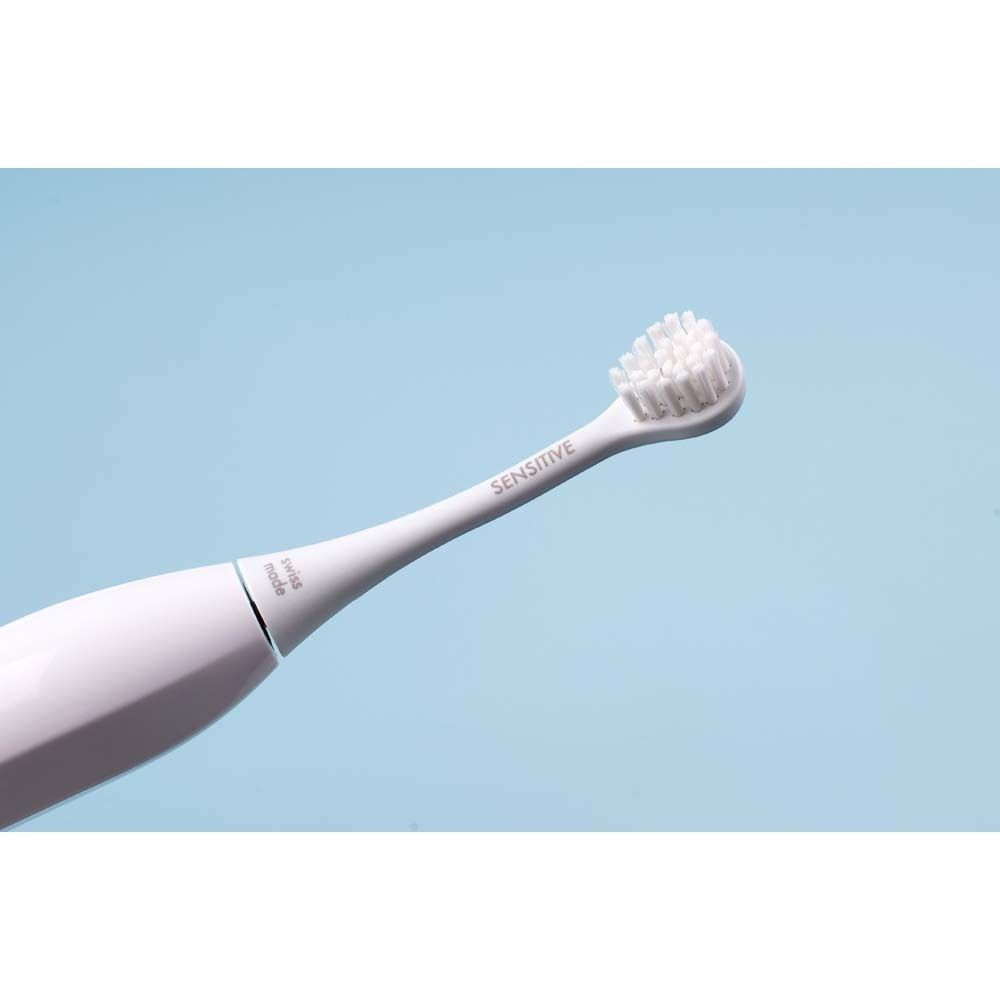 Tête de brosse blanche avec manche. Inscription "SENSITIVE". Swiss Made. Fond bleu.