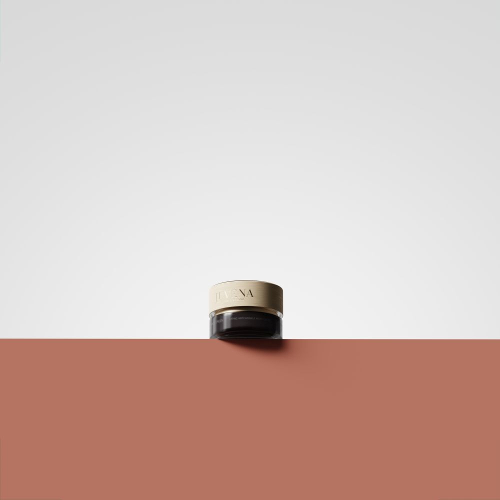 Creme-Tiegel mit goldfarbenem Deckel auf rotem Untergrund. Nur Deckel sichtbar. Aufschrift: Juvena.