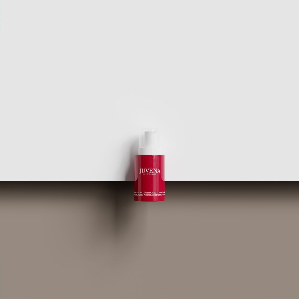 Rote Flasche mit weißem Pumpkopf. Aufschrift: JUVENA. Produkt steht auf braunem Untergrund vor weißem Hintergrund.