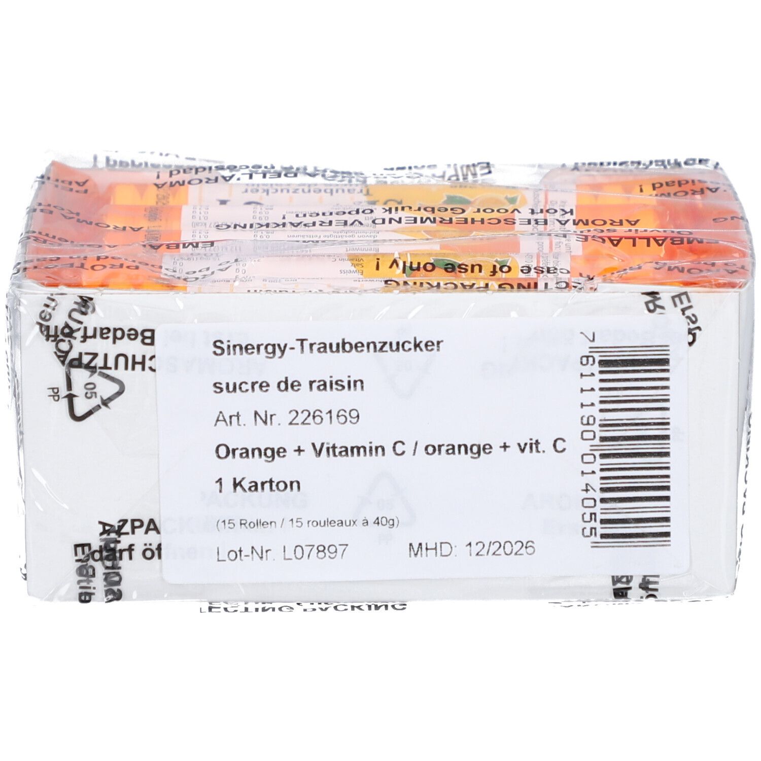 Weißer Karton mit Produktinformationen. Text: "SINERGY Traubenzucker", "Orange + Vitamin C". Barcode und Haltbarkeitsdatum.