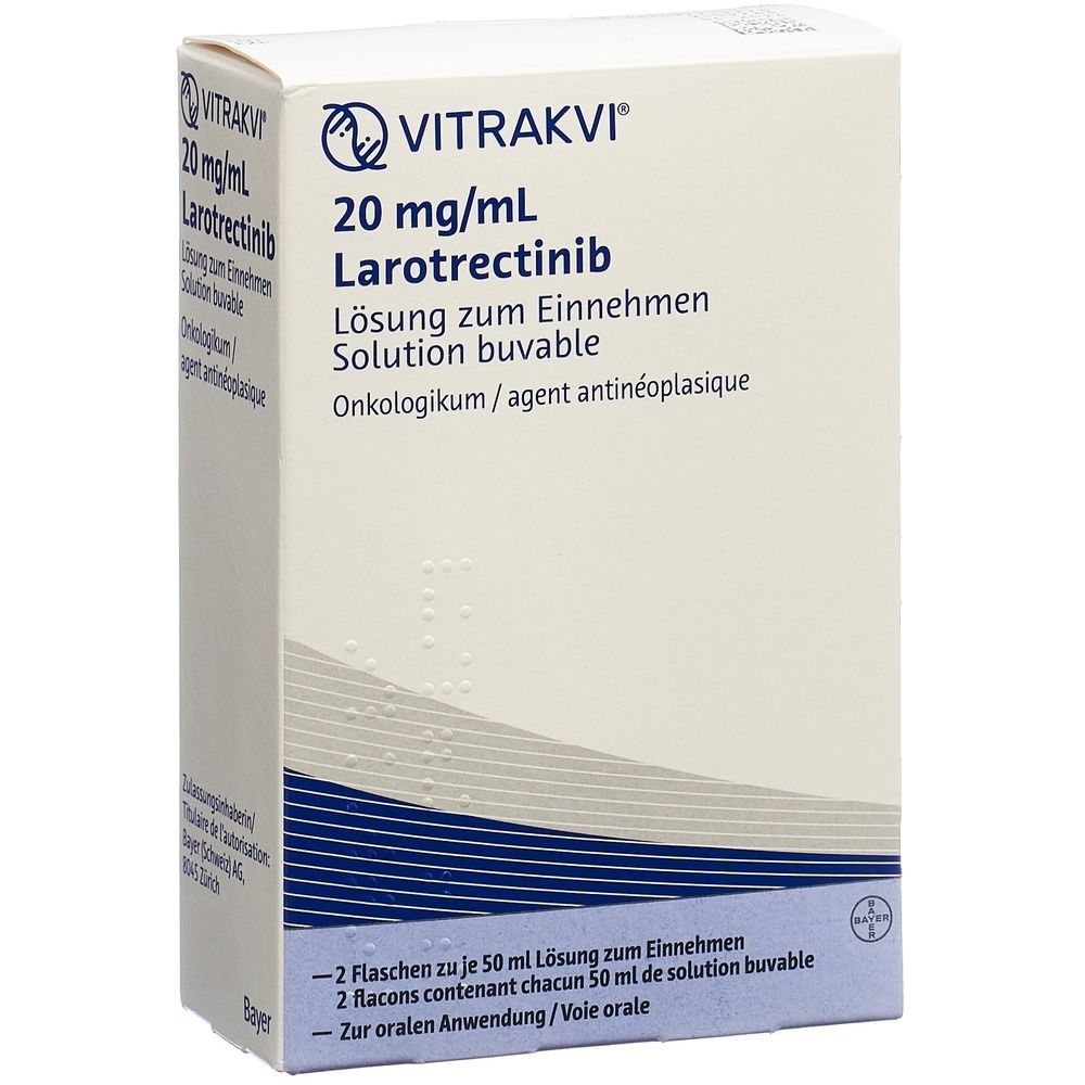 Boîte VITRAKVI Lös 20 mg/ml. Blanc, bleu et beige. Texte: 20 mg/ml, Larotrectinib. Inscription: Bayer.