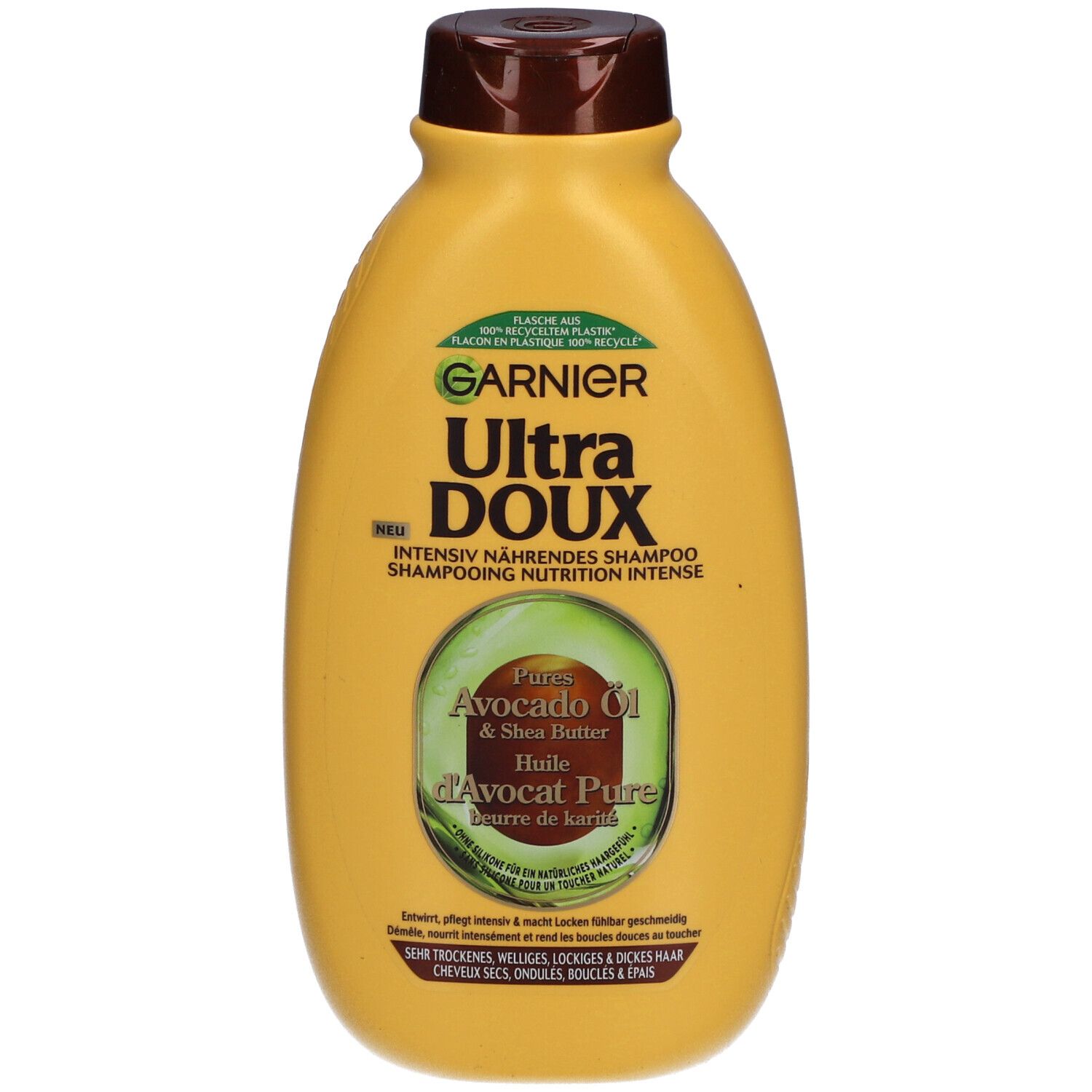 Flacon jaune, bouchon marron. Inscription: GARNIER Ultra DOUX, Huile d'Avocat & Beurre de Karité. Graphique vert et blanc.