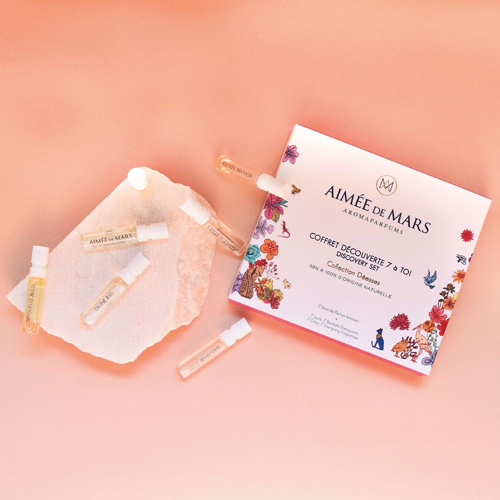 Parfümproben auf einem Stein. Geschenkset-Box im Hintergrund. Rosa Hintergrund. Mehrere kleine Glasfläschchen.