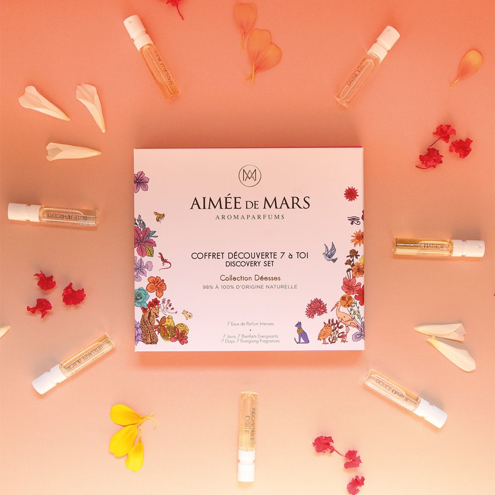 Parfümproben und Blütenblätter auf rosa Hintergrund. Geschenkset-Box in der Mitte. Mehrere kleine Glasfläschchen.