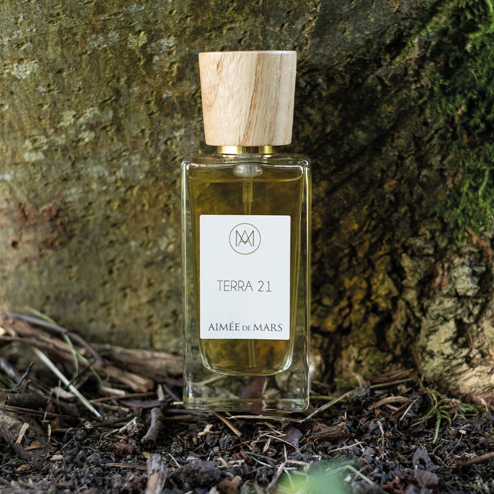 Glasflasche mit Holzverschluss vor Baumstamm. Aufkleber mit Text: Terra 21, Aimée de Mars.