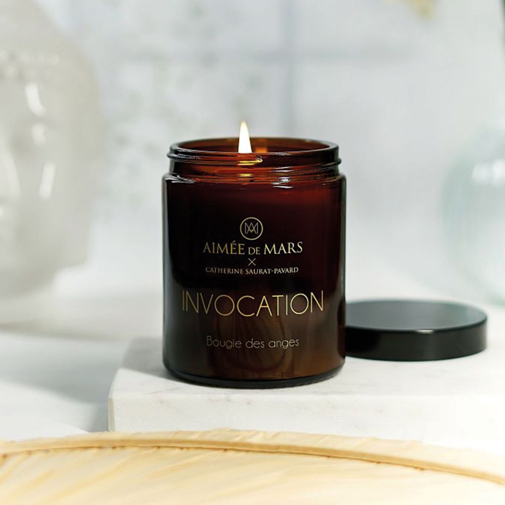 Brennende braune Duftkerze mit schwarzem Deckel. Goldener Schriftzug: Aimée de Mars, Invocation, Bougie des anges.