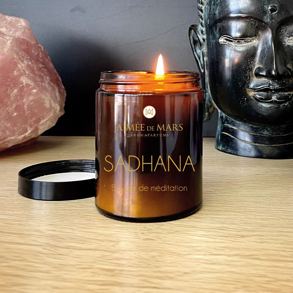 Bougie marron allumée avec couvercle noir. Inscription : AIMÉE DE MARS, SADHANA, Bougie de méditation.