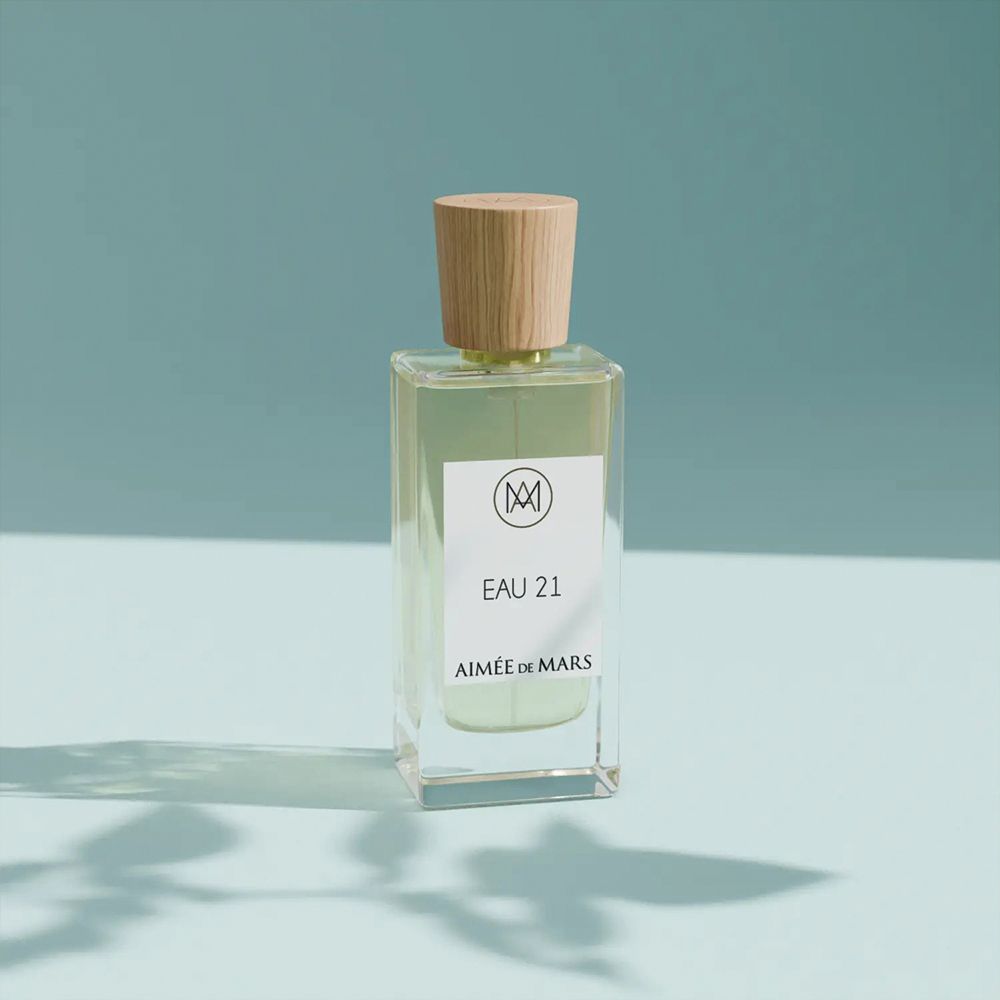Flacon de parfum avec bouchon en bois. Étiquette avec logo, "EAU 21" et "Aimée de Mars".