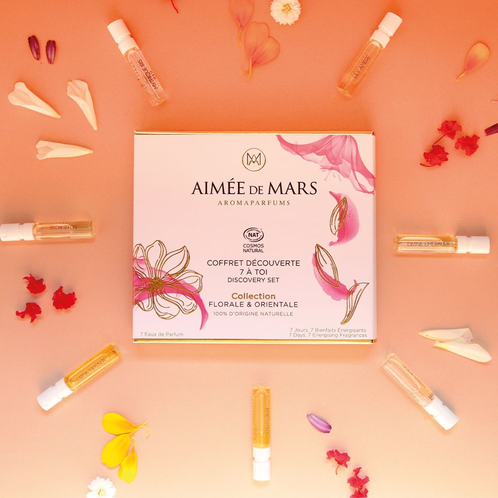 Aimée de Mars® Discovery Set Collection Florale. Eine Schachtel und sieben kleine Flakons auf rosa Untergrund. Blütenblätter.