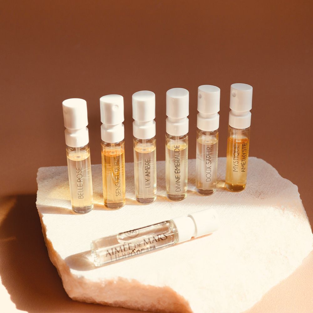 Sieben kleine Flakons mit verschiedenen Flüssigkeiten auf einem Stein. Aufschrift auf den Flakons.