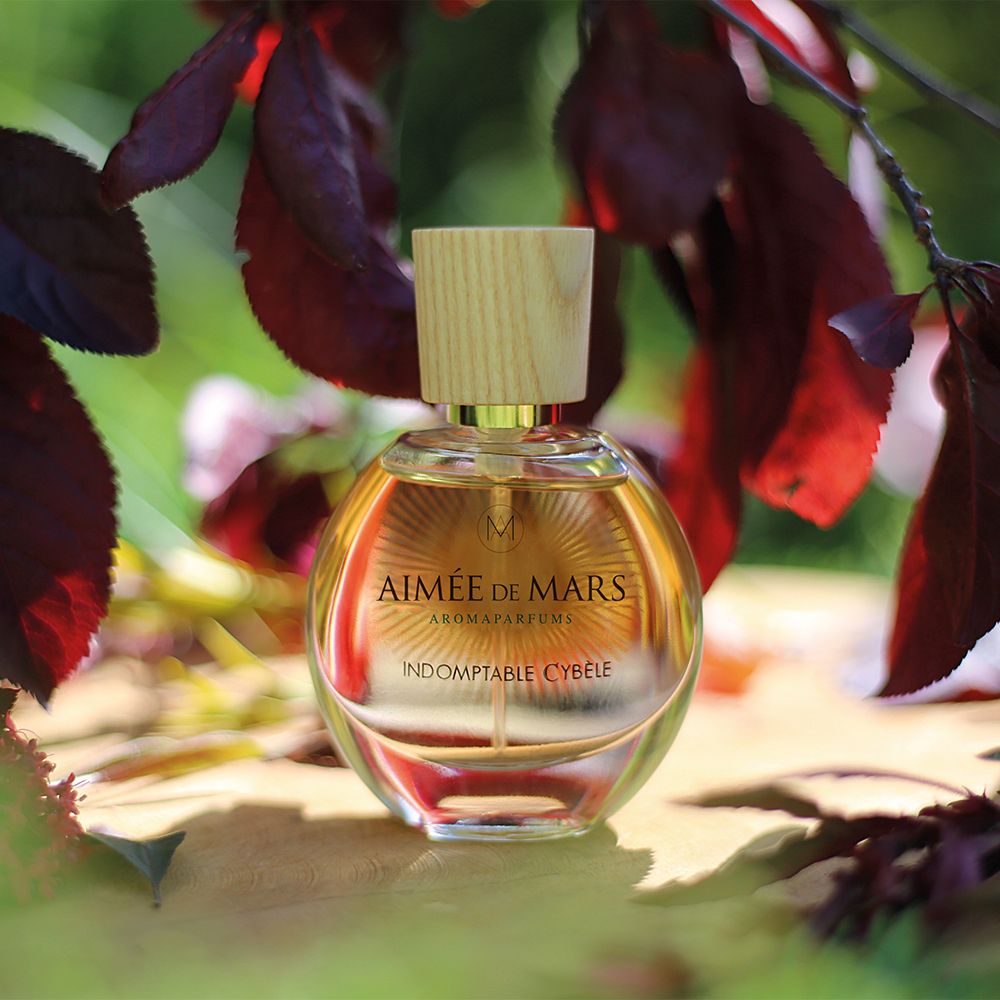 Runder Glasflakon mit Holzverschluss. Aufschrift: Aimée de Mars, Indomptable Cybèle. Aromaparfum.