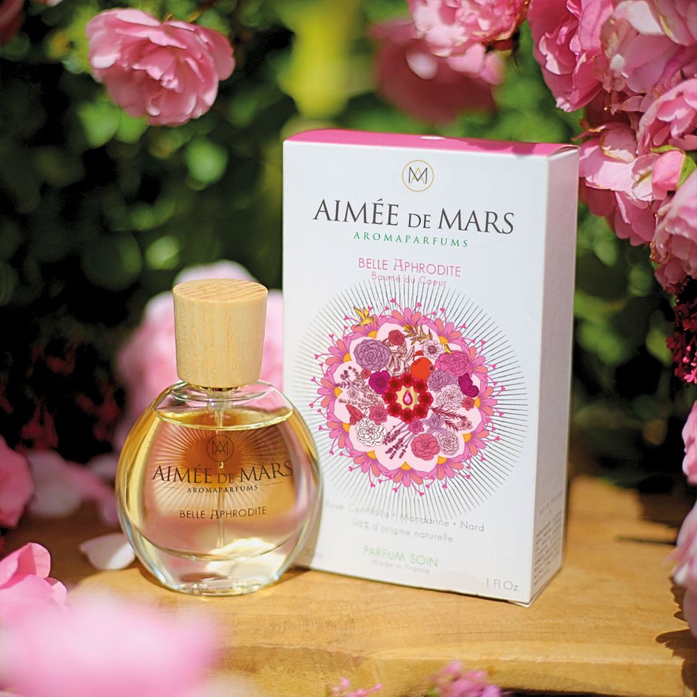 Parfümflakon und Verpackung. Aufschrift: Aimée de Mars, Belle Aphrodite. Blumenmuster. Rosen im Hintergrund.