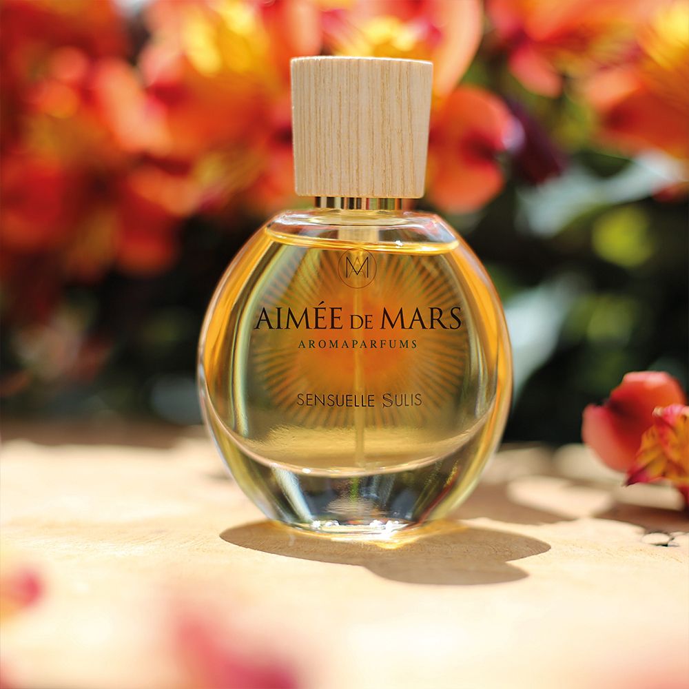 Runder Glasflakon mit Holzverschluss. Aufschrift: Aimée de Mars Aromaparfums, Sensuelle Sulis. Goldfarbene Flüssigkeit.
