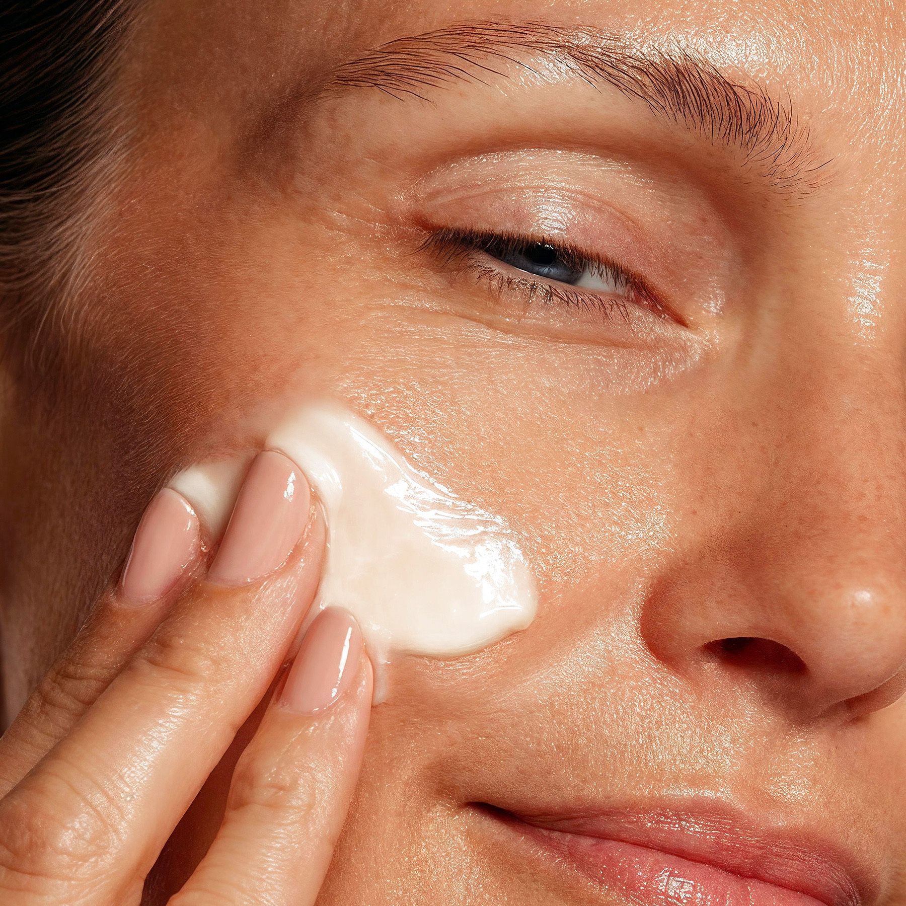 Nahaufnahme einer Frau, die Creme auf ihr Gesicht aufträgt. Hautpflege.