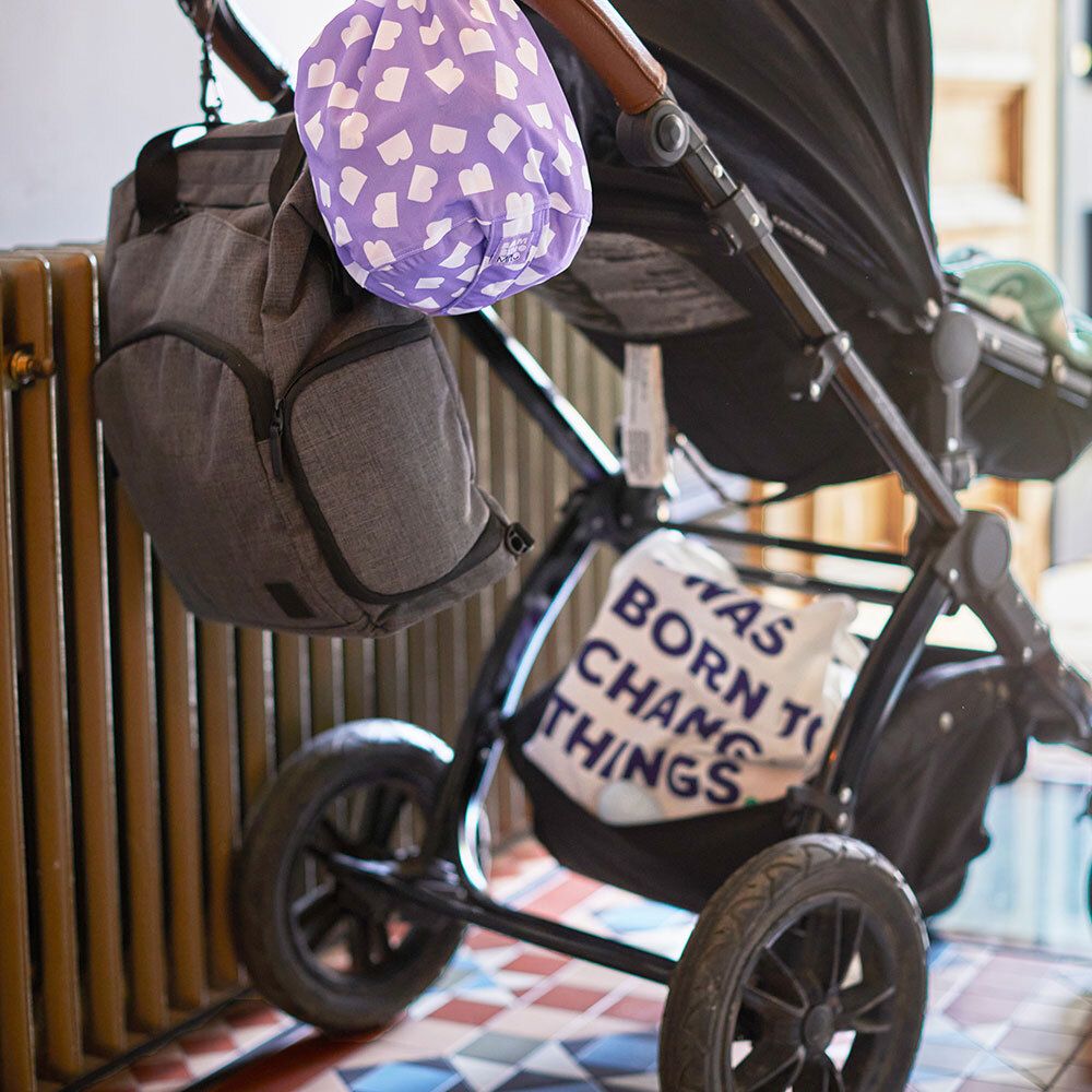 Sac violet à motifs nuages blancs, attaché à une poussette.